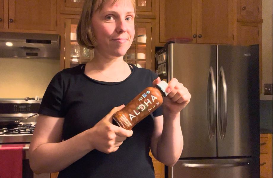 A woman open a bottle of ALOHA Protein Shake