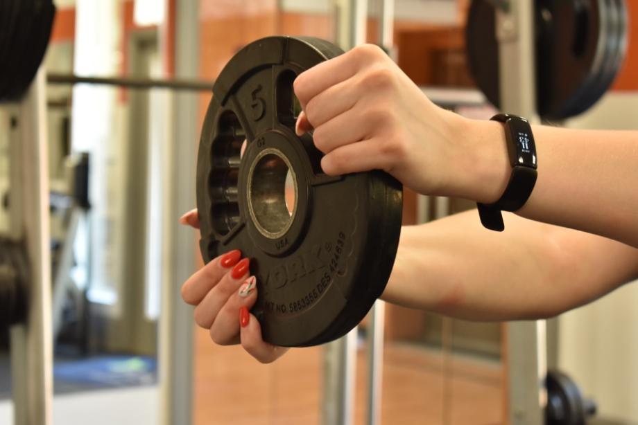 Person holding weight plate wearing Fitbit Inspire 2