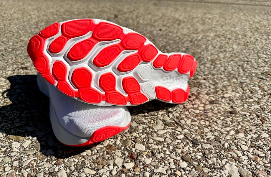 The tread of New Balance Fresh Foam sneakers is shown as the sneakers rest on a gravel pavement