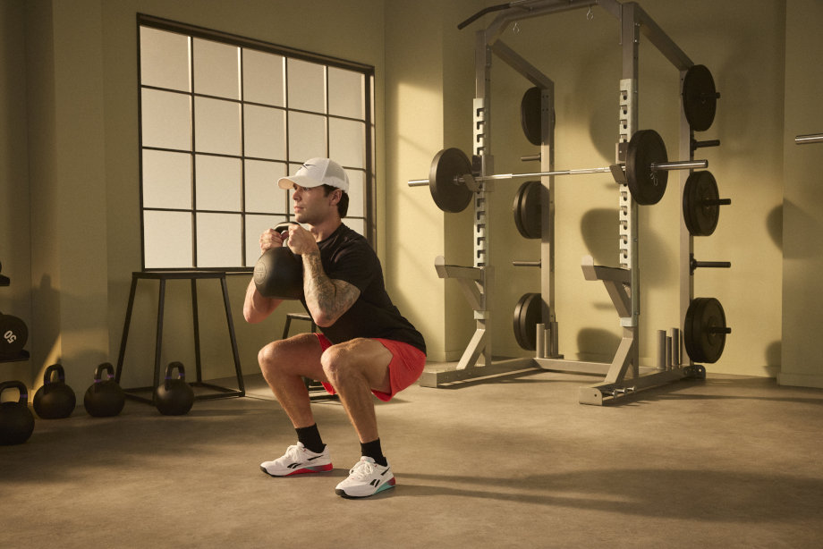 A man squats with a kettlebell while wearing a pair of Reebok Nano X5s. Image from Reebok