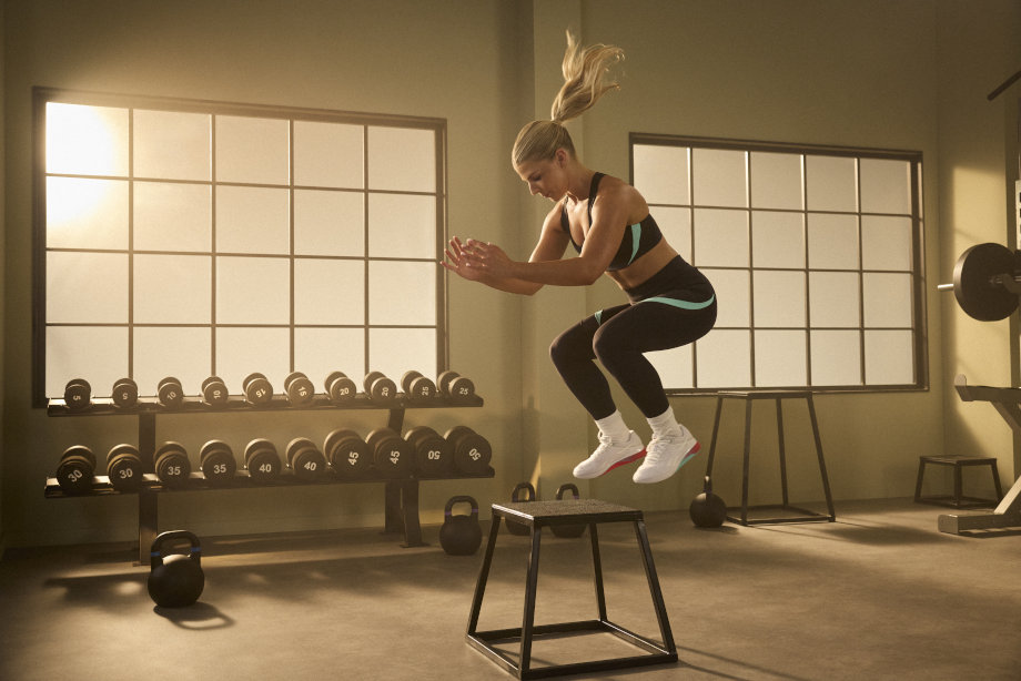 A woman jumps with Reebok Nano X5 shoes