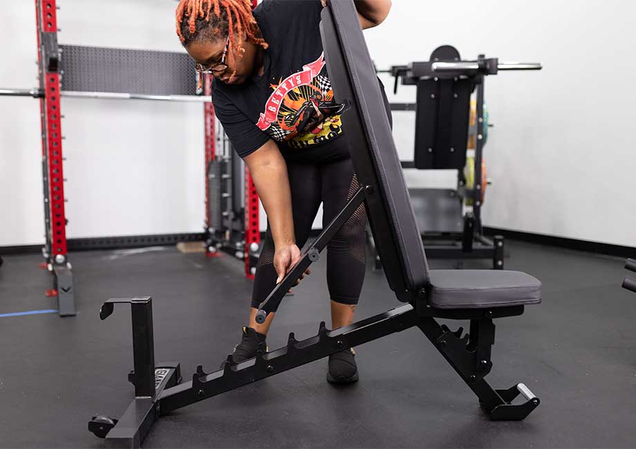 Woman in a gym adjusting the incline on a Giant 2X Adjustable Bench