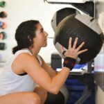 A woman holding a medicine ball during a set of wall ball squats