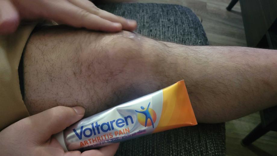 A person rubs Voltaren gel onto their knee.