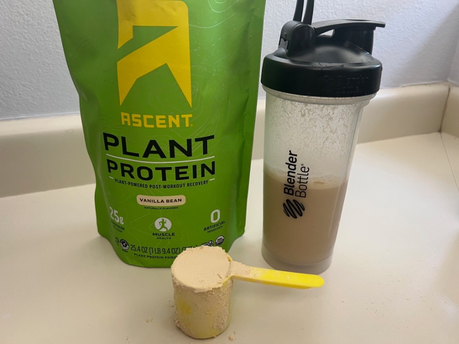 A scoop of Ascent Plant Protein rests next to the bag.