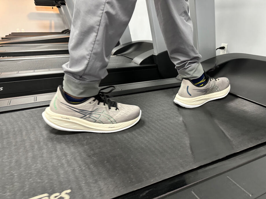 A person walks on a treadmill with Asics Nimbus 26 recovery shoes.