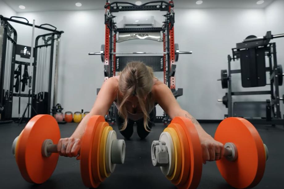 A woman does ab rollouts with Aviron Loadable Dumbbells.