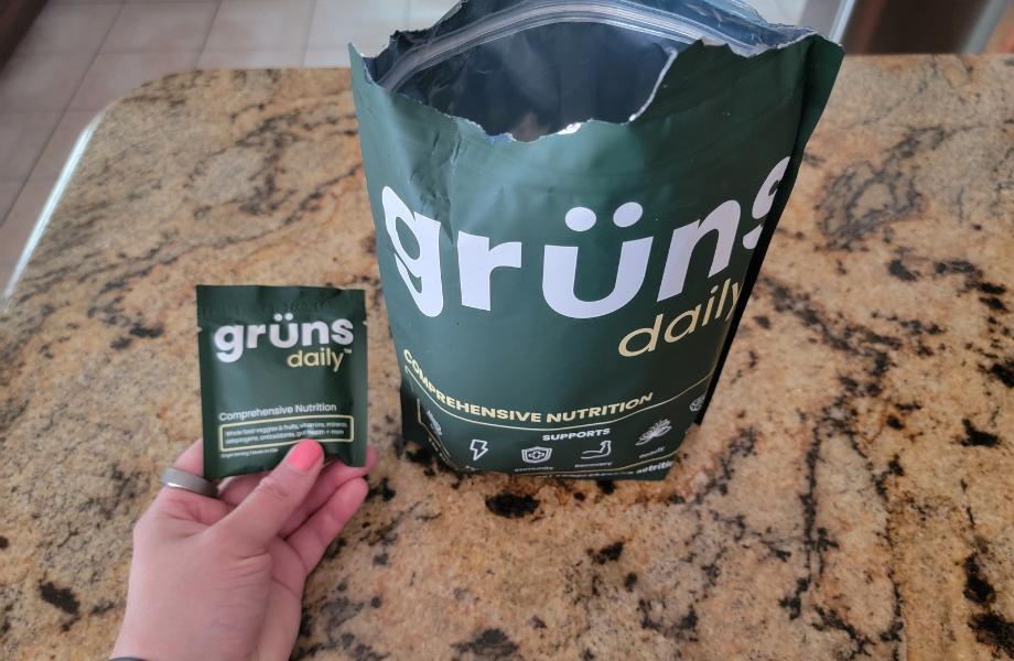 An opened bag of grüns gummies next to an individual snack pack