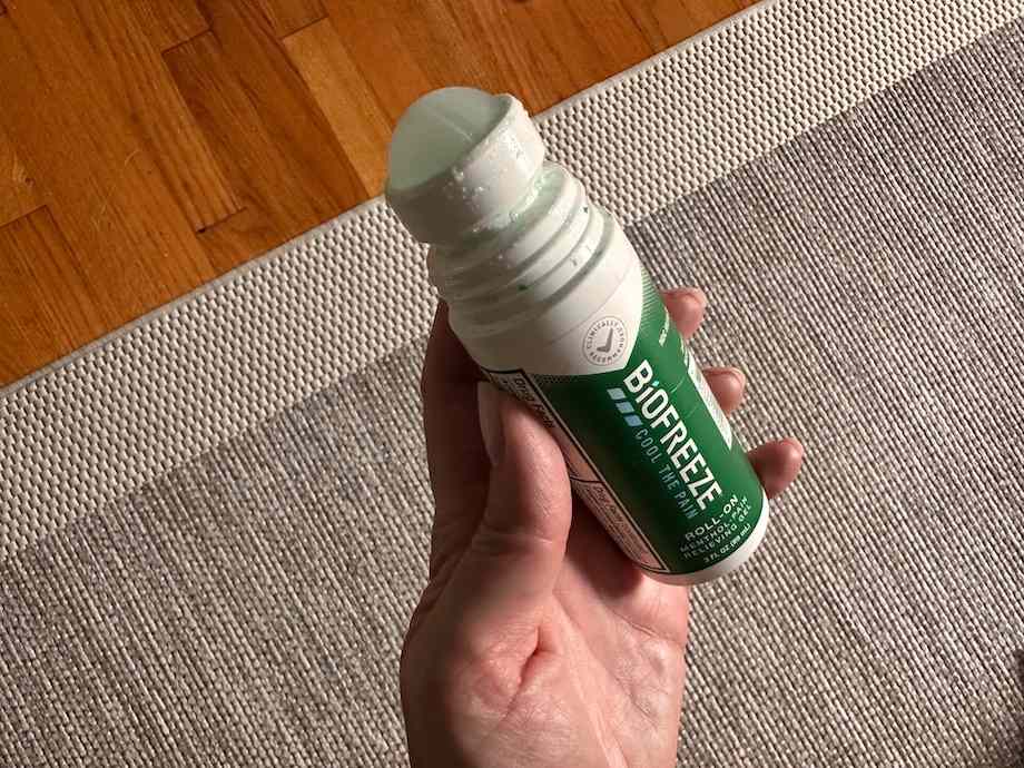 A person holding a Biofreeze roll-on without the lid.