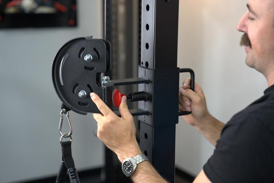 Man adjusting the trolley height on the uprights of the Body-Solid Functional Trainer Rack