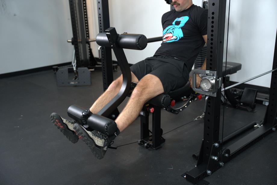 Man performing leg extensions using the GLEG Weight Bench on the Body-Solid Functional Trainer Rack