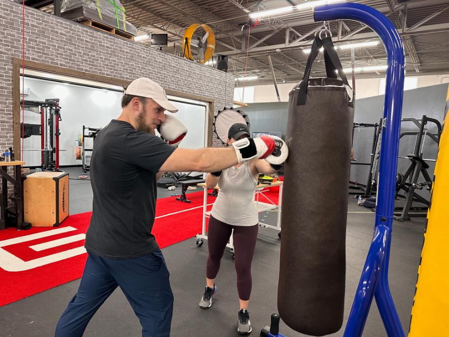 Man and woman punching a bag with boxing gloves