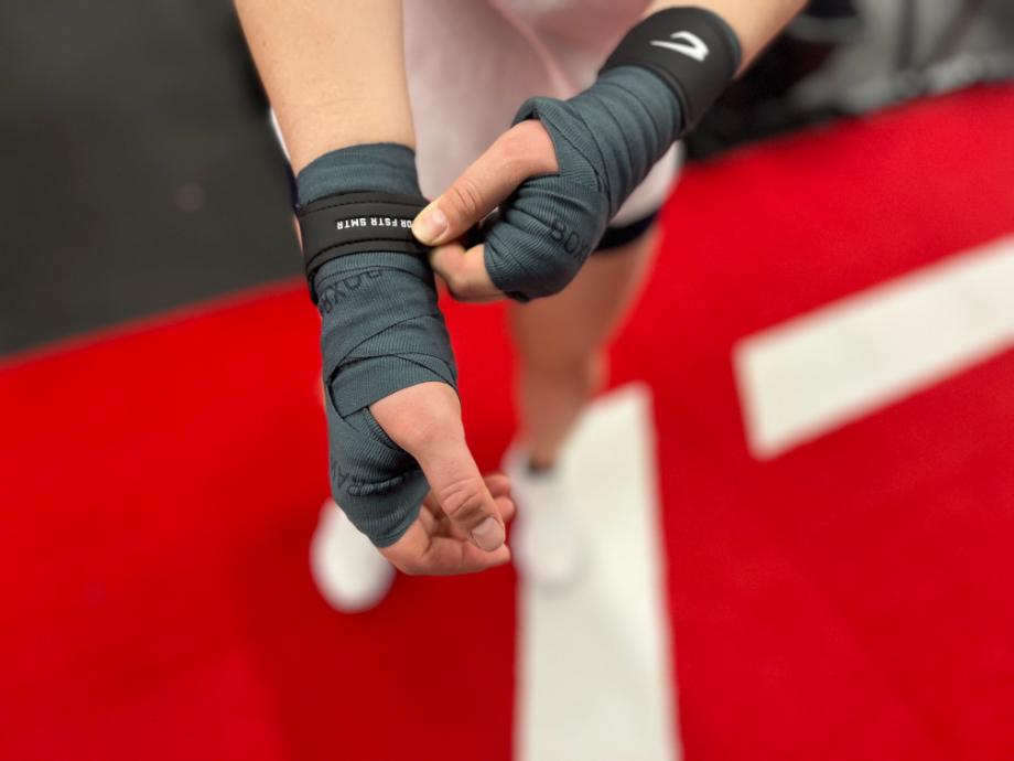 A person makes adjustments while wearing a pair of BOXRAW Hand Wraps.