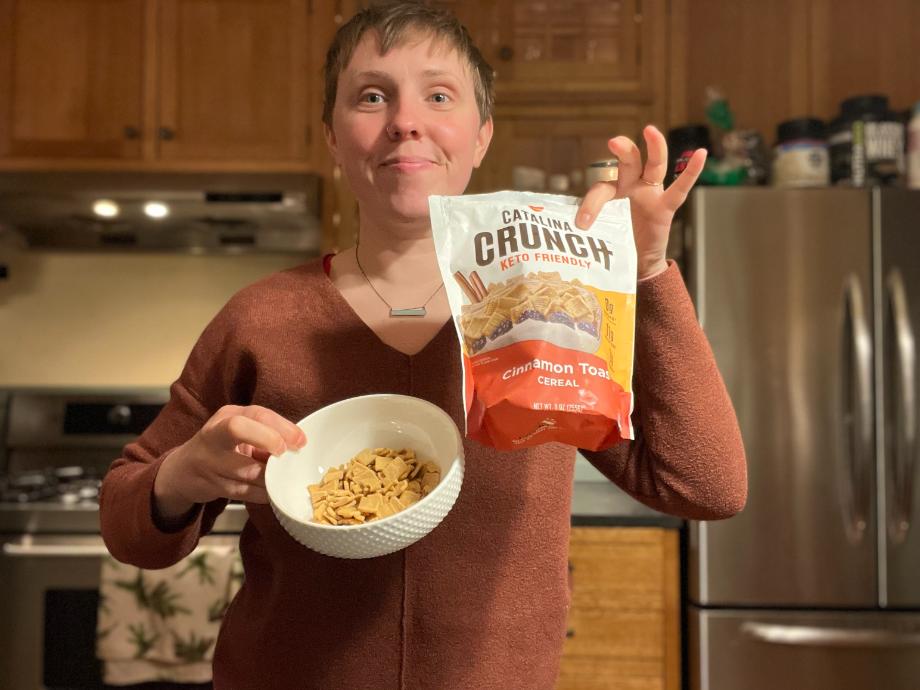 A woman holds up a bag of Catalina Crunch Protein Cereal.