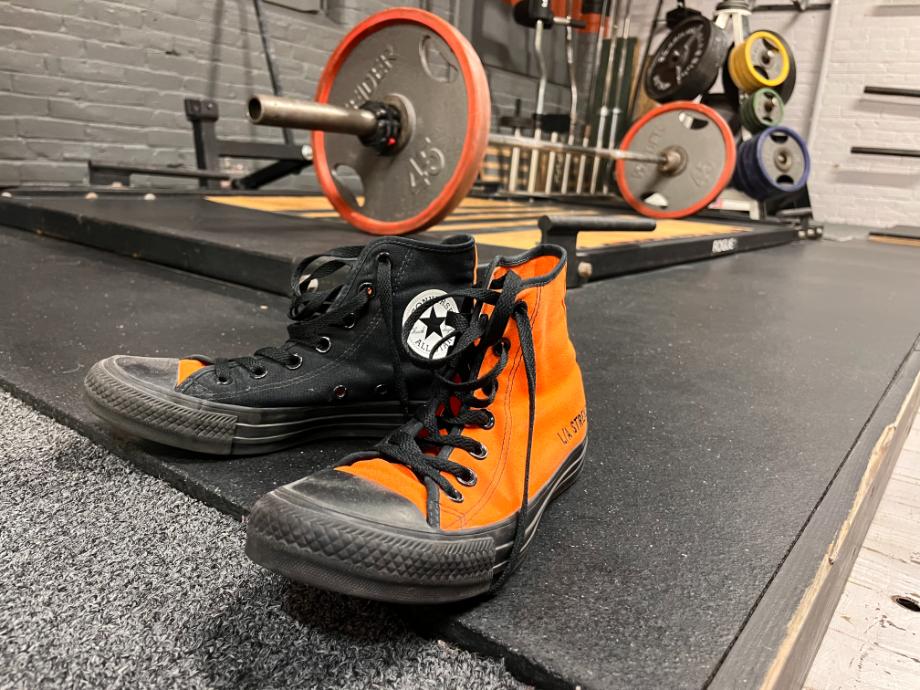 Orange and black Converse chuck taylor shoes in front of deadlift platform