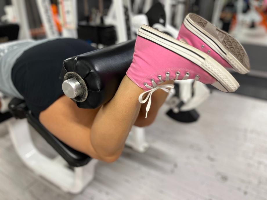 Woman wearing pink converse chuck taylors while performing leg curls