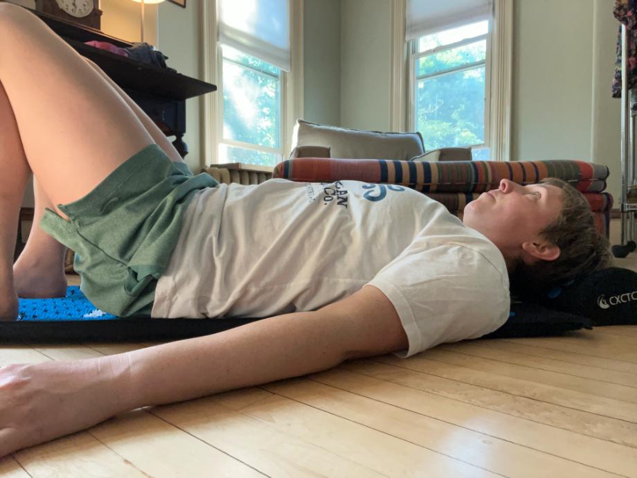 A person uses the CXCTCT Acupresssure Mat in a face-up position with knees bent.