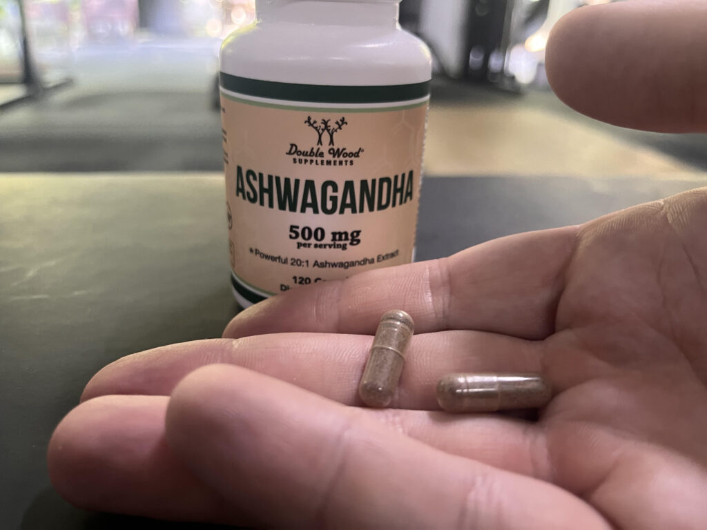 Person holding two capsules of Double Wood Ashwagandha