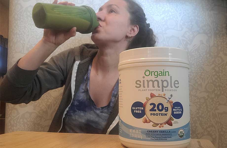 A person drinks an Orgain Simple Plant Protein shake.