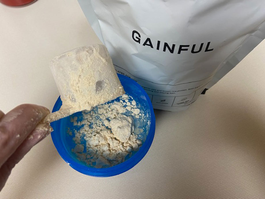 Dumping Gainful Vegan Protein Powder into a shaker cup