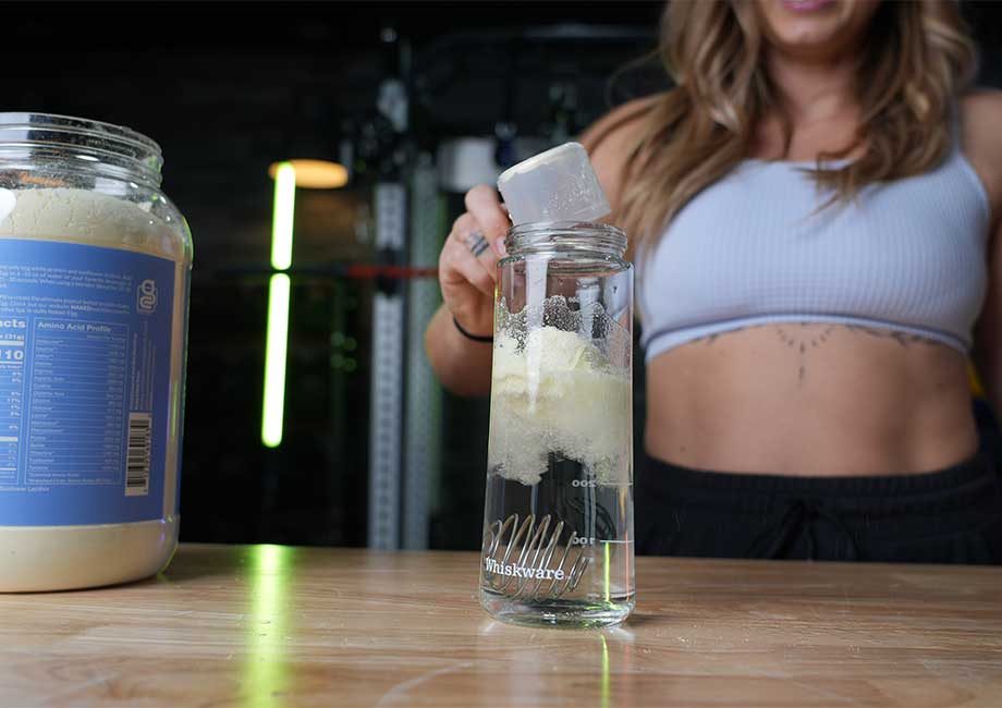 Lindsay dumps a scoop of Naked Egg protein powder into a shaker glass