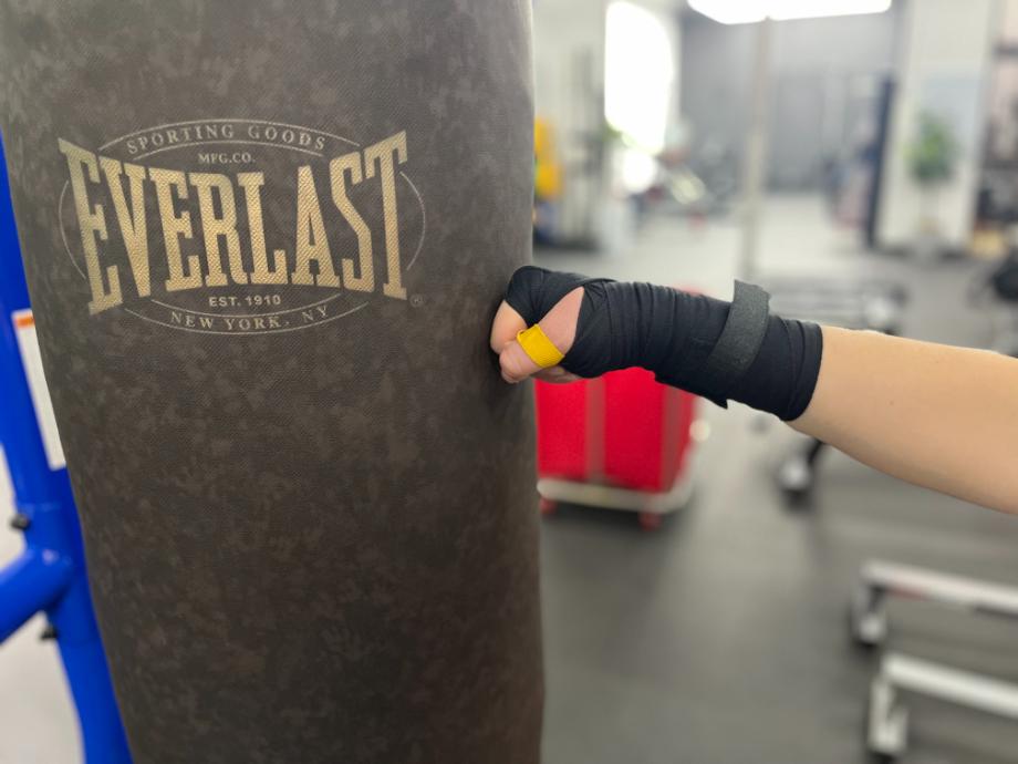 A person hits a punching bag while weraing Everlast Hand Wraps