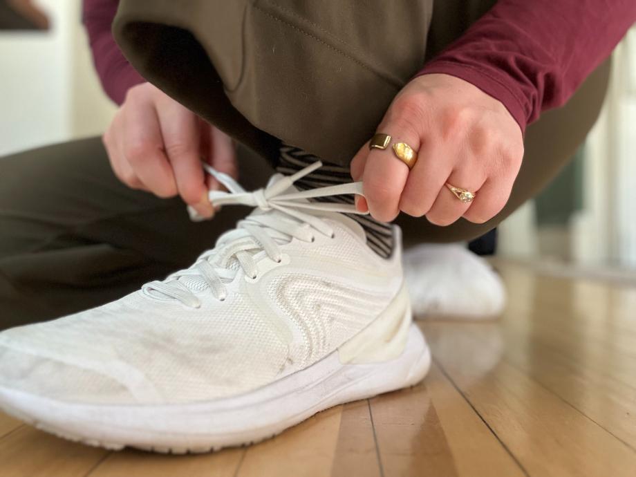 A person ties their shoes while wearing an Evie Ring