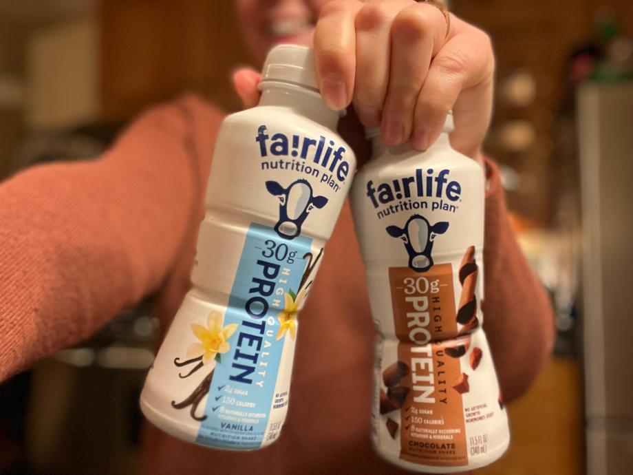 A person holds up chocolate and vanilla flavored bottles of Fairlife Nutrition Plan Shakes.