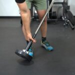 Coop picking up a Rogue Mace M20R barbell from the garage gym floor