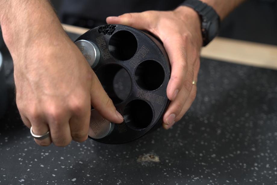 A person adds bullet weights to the Weight It Out Revolver plastic base