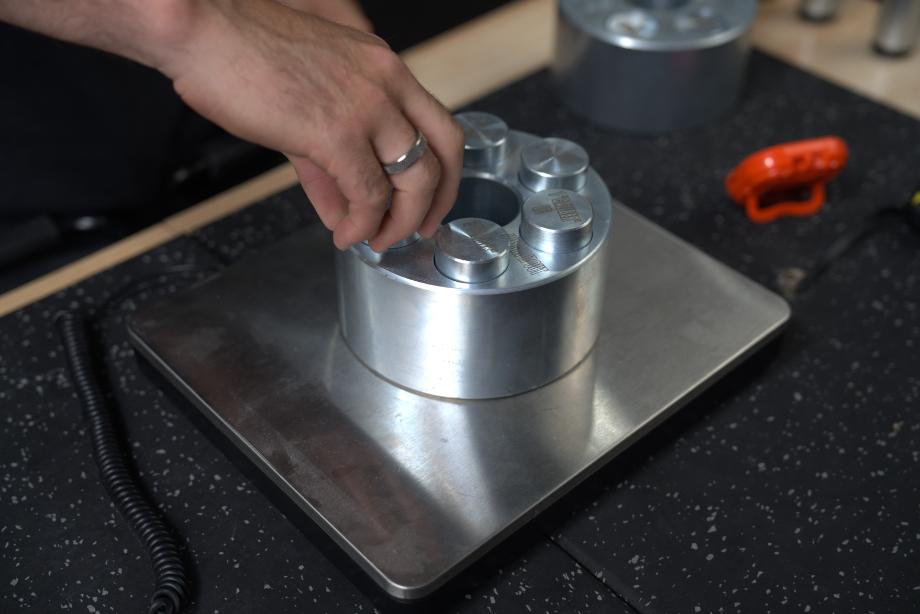 A person adds bullet weights to the stainless steel Weight It Out Revolver base