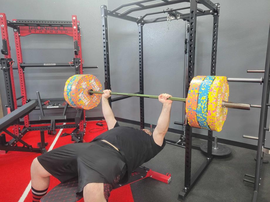 Man in a room with several racks bench pressing from the Giant Garage Gym Power Rack 2.0