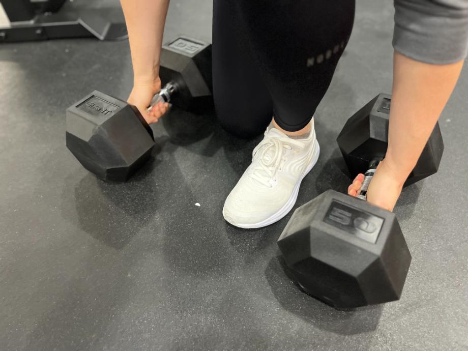 Person kneeling to grab 50-pound Giant Lifting Hex Dumbbells