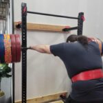 Man wearing a red lifting belt preparing for a back squat on the Giant Lifting Wall Rack 2.0