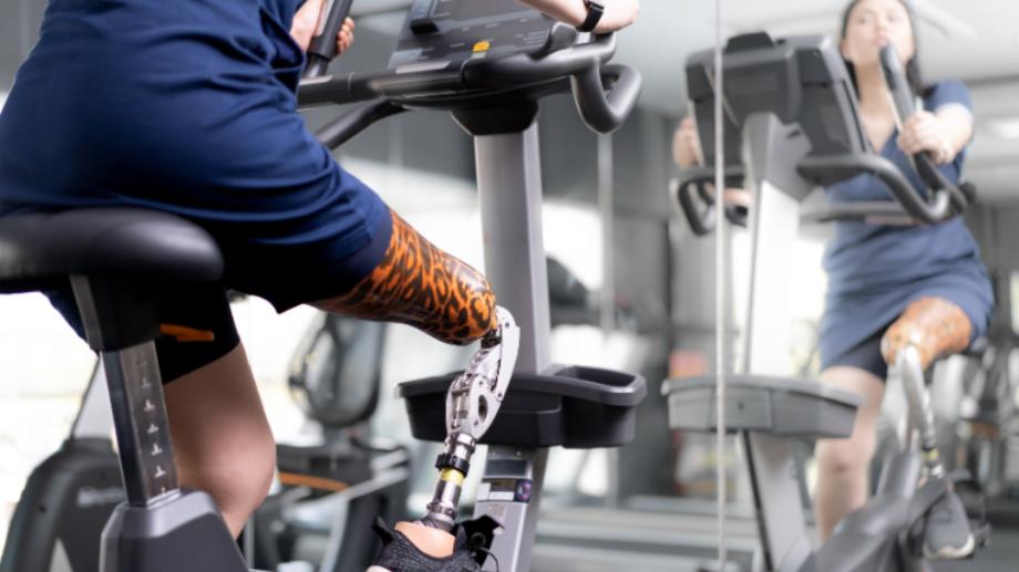 An athlete with a lower-body amputation rides a stationary exercise bike for the gym accessibility guide. Credit: NassornSnitwong / Shutterstock