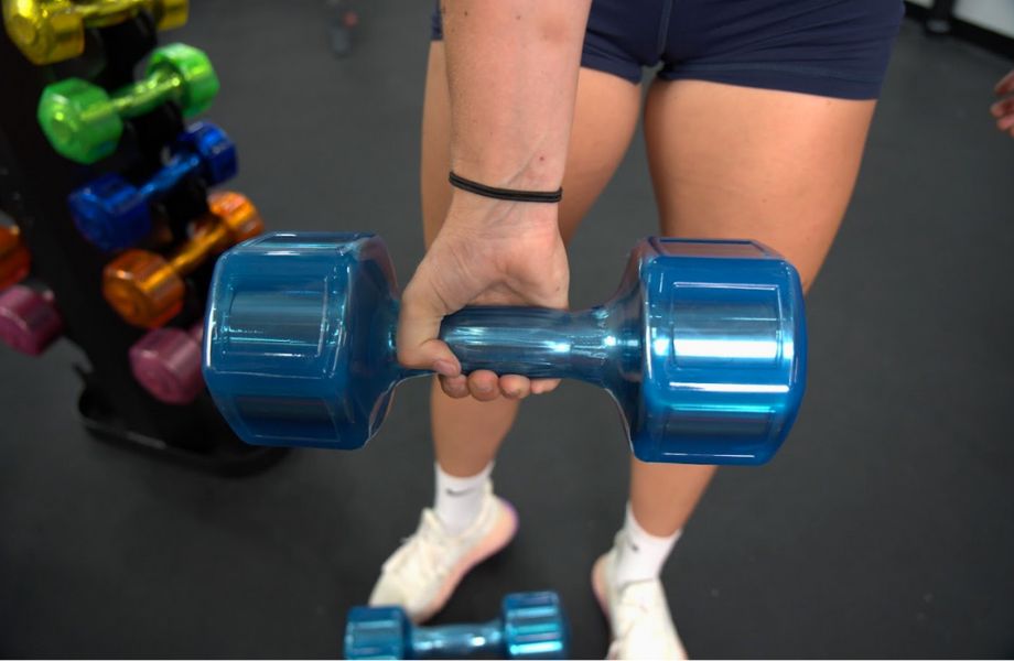 Woman holding light blue urethane coated Jelly Bell dumbbell