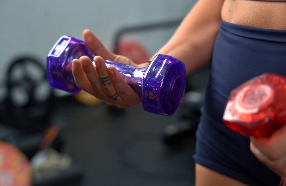 Woman holding purple urethane coated Jelly Bell dumbbell