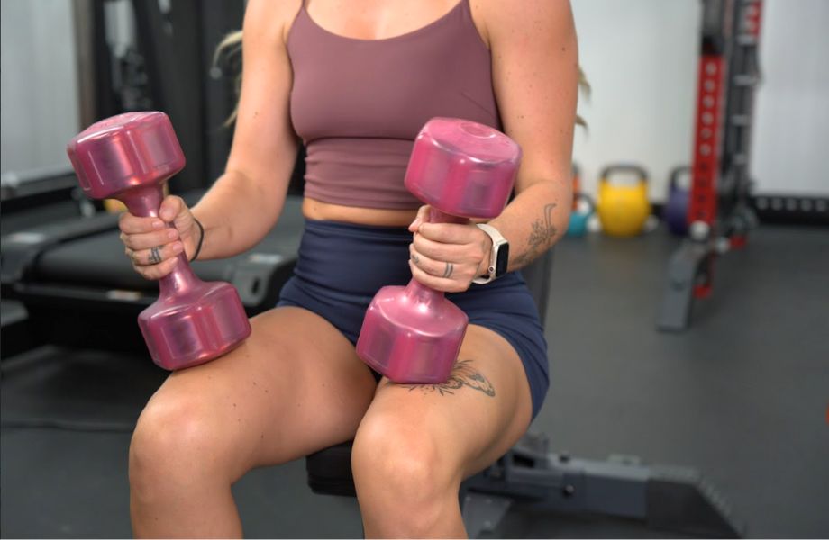 Woman holding pair of Hampton Jelly Bell on legs before overhead press