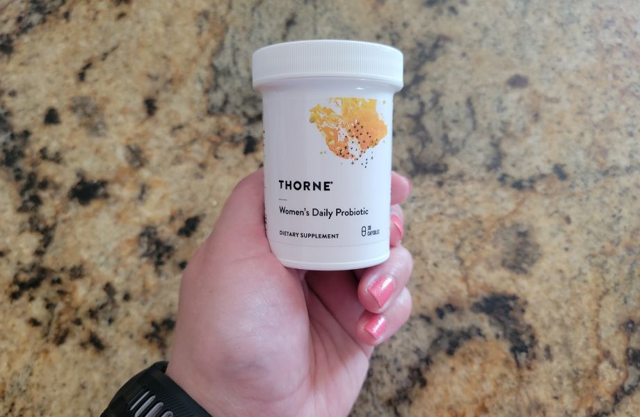 Hand holding a bottle of Thorne Women's Daily Probiotic.