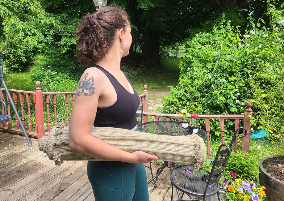 Woman holding a rolled up Oko yoga mat under her arm