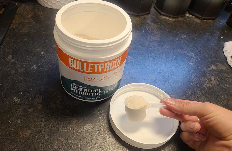 Holding a scoop of Bulletproof InnerFuel Prebiotic in front of the container.