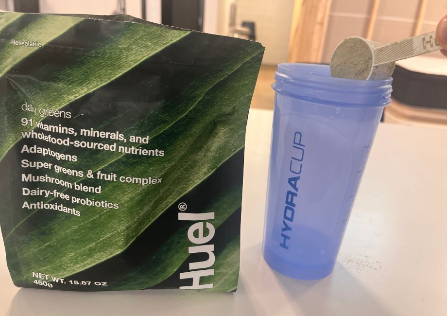 Huel Daily Greens being poured into a shaker bottle