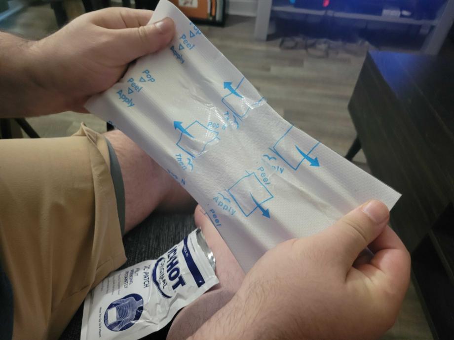 A person breaks open an Icy Hot patch.