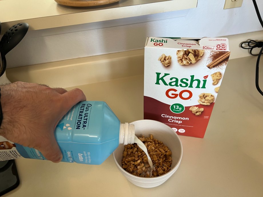 Milk is being poured into a bowl of Kashi GO Protein Cereal.