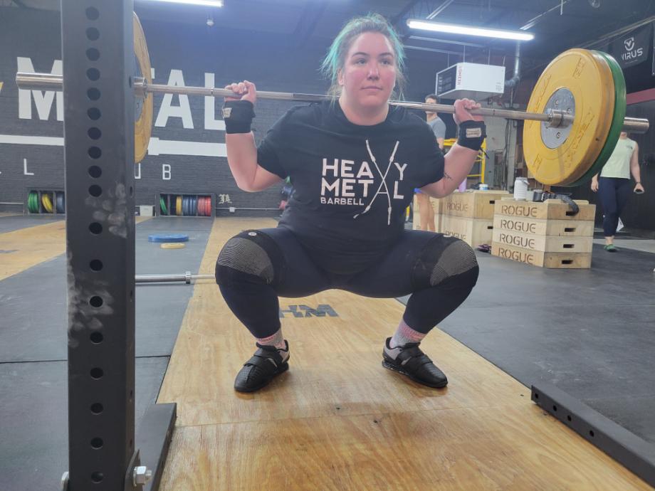 A person does a back squat in kcross Weightlifting Shoes.