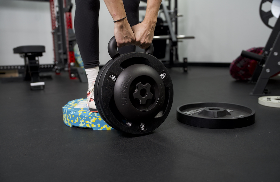 A woman holds a loaded Kensui EZ-BELL MAX to perform RDLs.