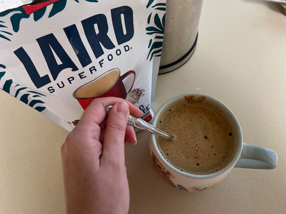 A person stirs a mug of Laird Superfood Mushroom Coffee.