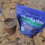 Chocolate-flavored L'Evate You Greens Powder mixed into a glass of water.