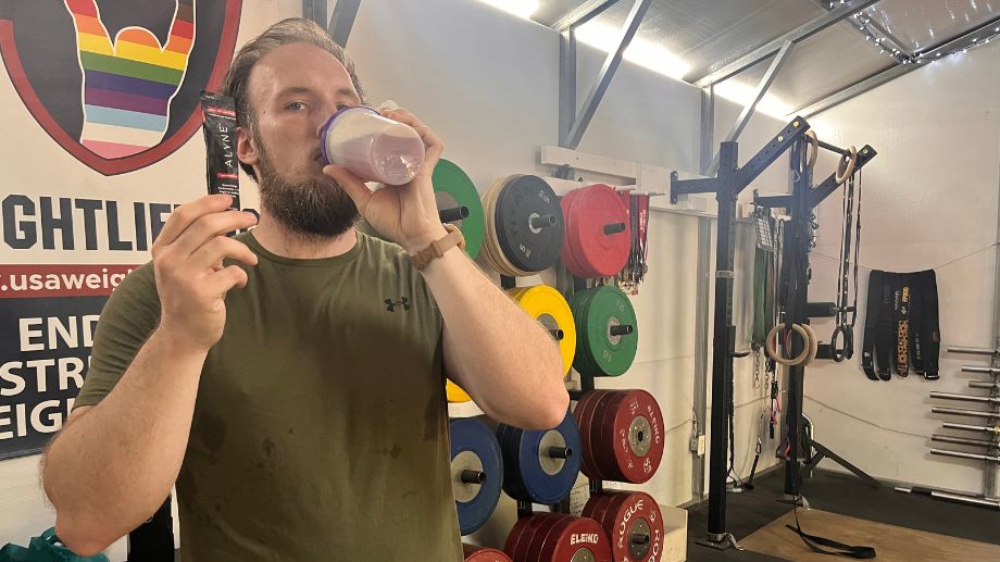 A man in a gym drinking Alyne pre-workout