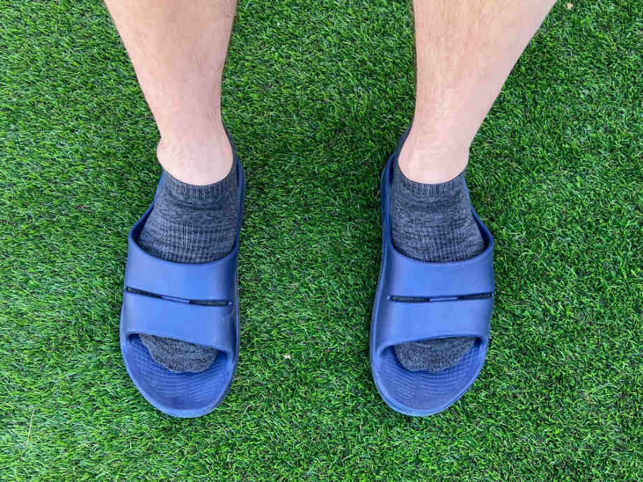 A man wearing OOFOS Recovery Slides.